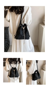 Detail of black drawstring bucket bag with butterfly metal buckle and pearl charms