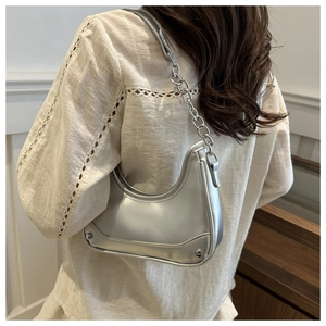 Detail of silver crescent baguette bag with metallic leather and chain strap on shoulder