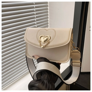 Close-up of beige crossbody bag featuring heart metal buckle and wide woven shoulder strap