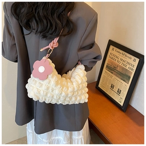 Close-up of a white bubble textured cloud bag with a pink flower charm and shoulder strap