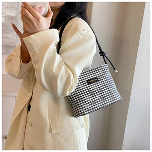 Detail of houndstooth crossbody bag featuring unique knotted shoulder strap on blazer