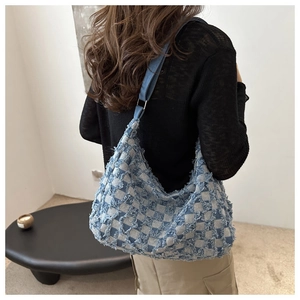 Détail d'un sac hobo en denim à carreaux bleu et blanc avec finitions à bords effilochés