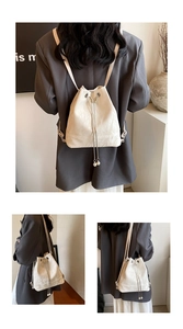 Detail of off-white bucket bag featuring drawstring closure and elegant pearl pendants