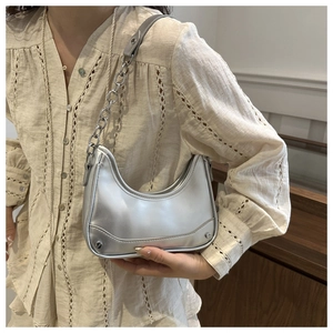 Close-up of metallic silver crescent bag with chunky chain strap and rivet details
