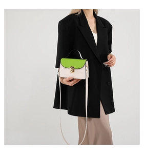 Detail of green and beige crossbody bag with gold twist lock and matte leather texture