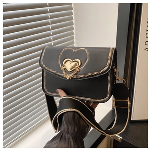 Detail of a black leather crossbody bag featuring a golden heart lock and woven strap