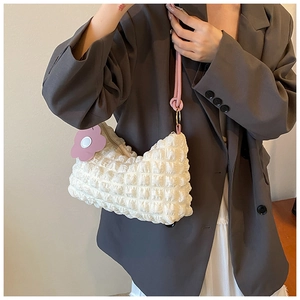 Detail of cream waffle textured hobo bag with pink strap and floral charm on a model