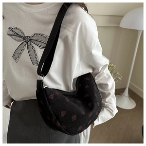 Detail of black corduroy dumpling bag with red strawberry pattern and wide strap