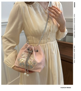 Détail de broderie sur sac seau en satin rose avec chaîne argentée et perles blanches