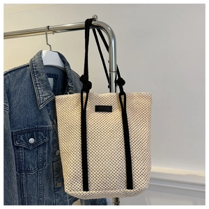Detail of hollow woven tote bag with honeycomb texture and black rope handles