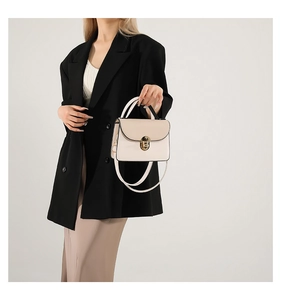 Detail of beige soft leather crossbody bag with gold hardware and black edge paint