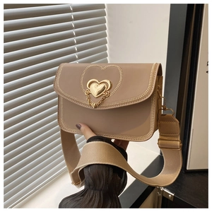 Detail of beige crossbody bag with gold heart clasp and decorative embroidery