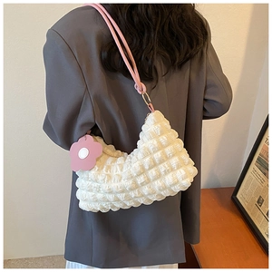 Detail showing white bubble textured bag with pink floral pendant and shoulder strap