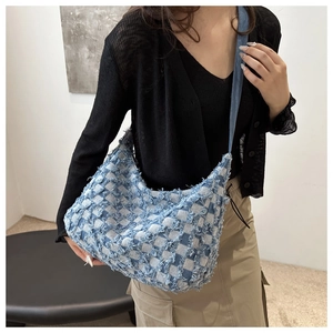 Détail du sac croissant en denim bleu et blanc avec texture à carreaux effilochés