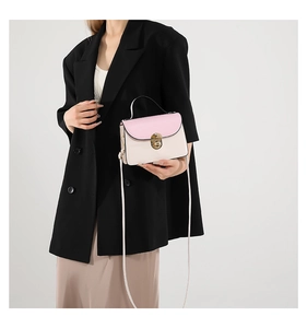 Detail of pink and beige crossbody bag with gold twist lock on black blazer outfit