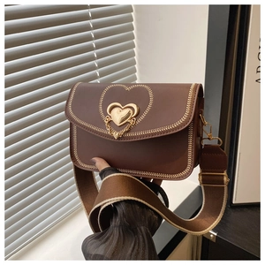 Detail of dark brown leather crossbody bag featuring heart embroidery and gold metal clasp