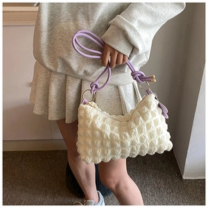 Close-up of white bubble texture bag with purple straps and cute flower pendant