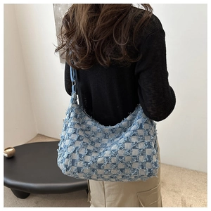 Détail du sac hobo en toile à damier avec des bords effilochés vintage et des franges