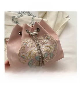 Detailed embroidery view of pink bucket bag with gold floral patterns and pearl drawstring