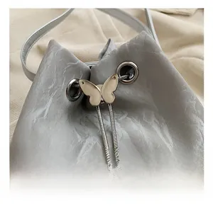 Detail of silver butterfly drawstring buckle on gray marble pattern bucket bag