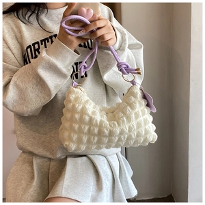 Detail of white popcorn textured bag with purple strap and cute cloud charm accessory