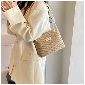 Dettaglio della borsa a spalla in paglia intrecciata con etichetta Fashion e tracolla