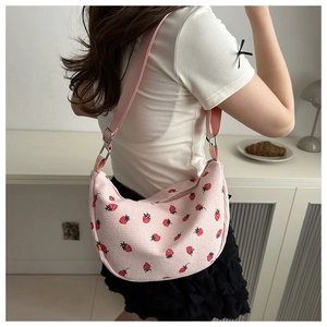 Detail view of pink corduroy dumplings bag with red strawberry pattern and shoulder strap