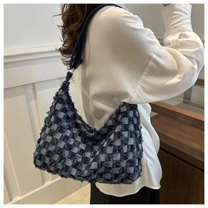 Détail du sac en denim à damier bleu avec bords effilochés et large bandoulière tissée