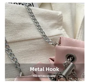 Close-up of silver metal hook and chain on pink suede bucket bag with embroidery detail