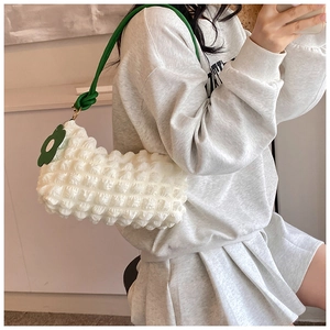Detail of white bubble texture bag with green handle and green flower charm