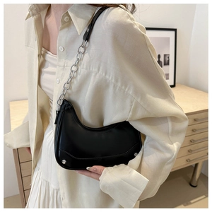 Close-up of black saddle bag with silver chunky chain and minimalist rivet accents