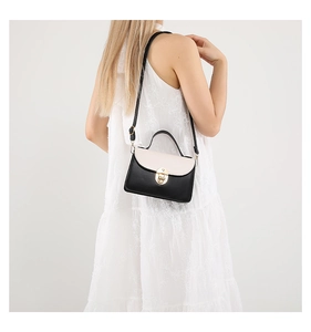 Detail of elegant black and white contrast leather handbag with golden metal lock and strap