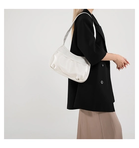 Detail of white PU leather crescent bag with minimalist pleats and wide shoulder strap
