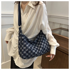 Détail du sac hobo en denim à damier avec bords effilochés et bandoulière bleue réglable