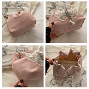Detail view of pink satin bucket bag with floral embroidery and large pearl charms