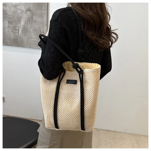 Close-up of hollow straw tote bag featuring contrast rope straps and smooth fabric lining