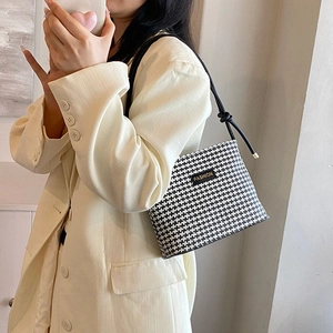 Chic black and white houndstooth pattern bucket bag with fashion label and knotted strap
