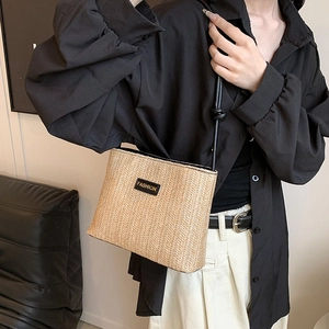 Minimalist straw bucket bag with black leather logo patch and slim shoulder strap