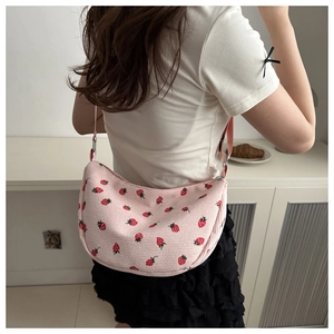 Pink corduroy bag with strawberry pattern shown in use by a model from the back