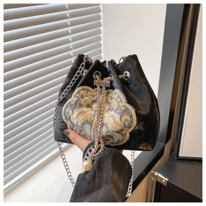 Detail of floral embroidery and pearl drawstring on black velvet bucket chain bag