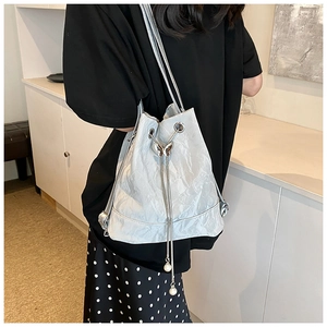 Detail of silver bucket bag featuring pleated texture and butterfly metal buckle
