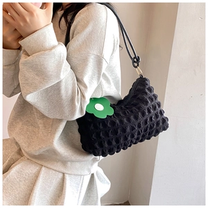 Detail of black pleated shoulder bag with texture fabric and cute floral charm