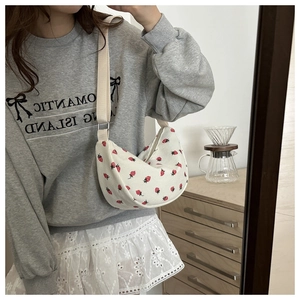 Detail of white corduroy dumpling bag with red strawberry pattern and canvas strap