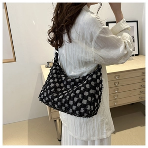 Détail du sac hobo à damier en tweed texturé, porté à l'épaule par un mannequin