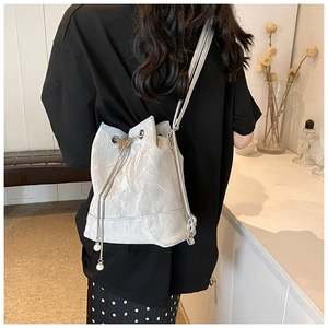 Detail of silver bucket bag with pleated texture, butterfly charm and pearl drawstrings