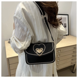 Detail of crossbody bag featuring heart metal lock and contrast stitching on black leather
