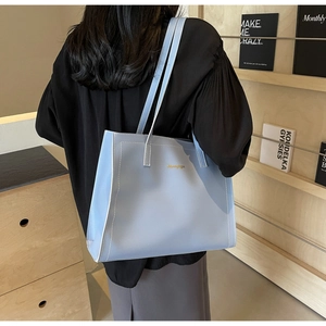 Close-up of light blue leather tote bag with white stitching and gold lettering detail