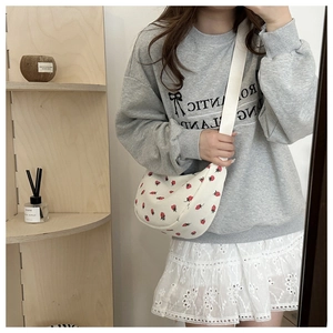 Lifestyle shot of white crescent crossbody bag with strawberry print and wide strap