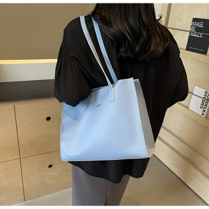 Close-up of light blue leather tote bag with white contrast stitching and thin shoulder straps