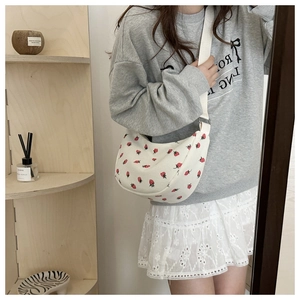 Detail of white corduroy moon bag featuring red strawberry print and adjustable strap